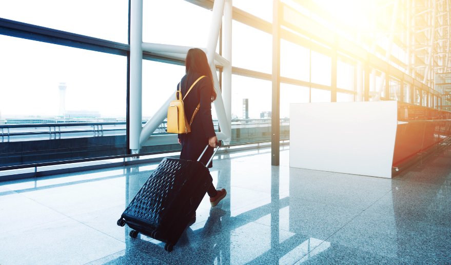 A woman pulls a wheeled suitcase behind her in an airport as she travels