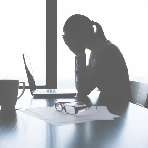 Exhausted woman in an office with her hands on her face because of low employee engagement