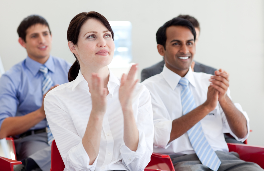 International business people clapping at a conference on corporate language training