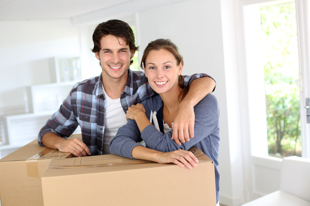 Man and woman smiling while leaning on a packing box. They have completed language training for relocating employees.