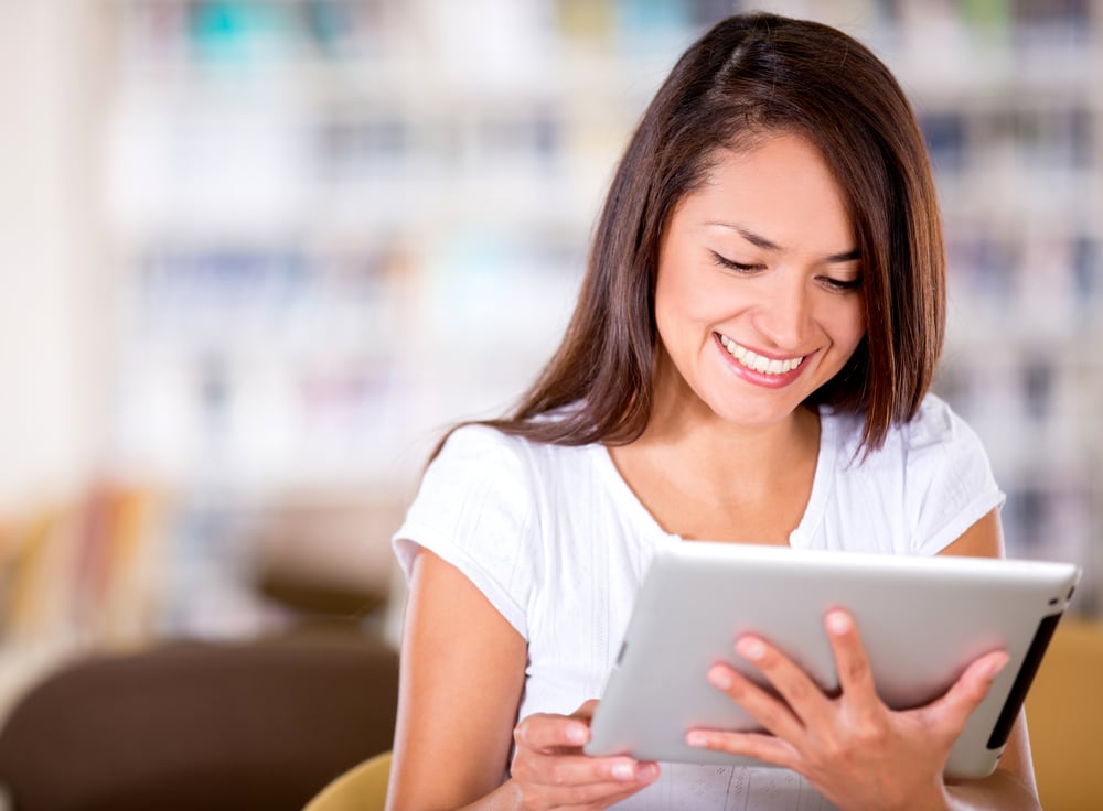 Woman smiling using a tablet to access her online language training platform