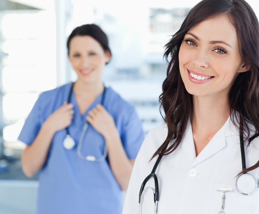 A doctor and a nurse with stethoscopes smiling in a bilingual workplace