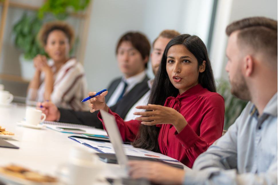 Group of non-native speaking business people at a conference table discussing DEI initiatives