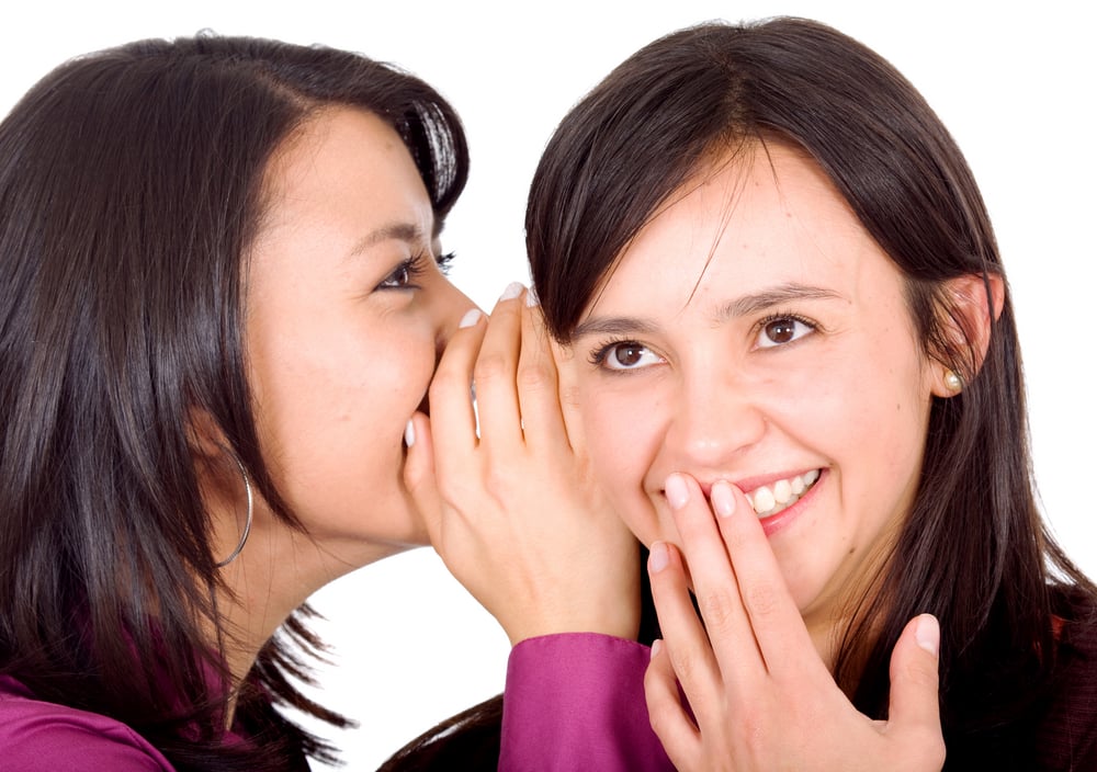 Two girls telling each other secrets with slang learned through language training