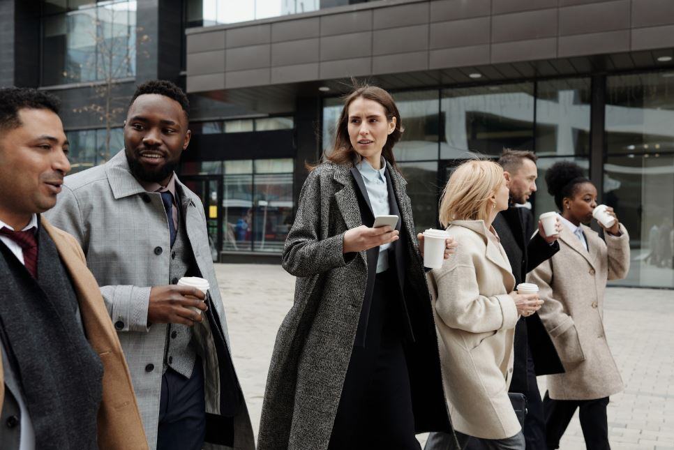 A diverse group of coworkers walking outside with coffee discussing intercultural training